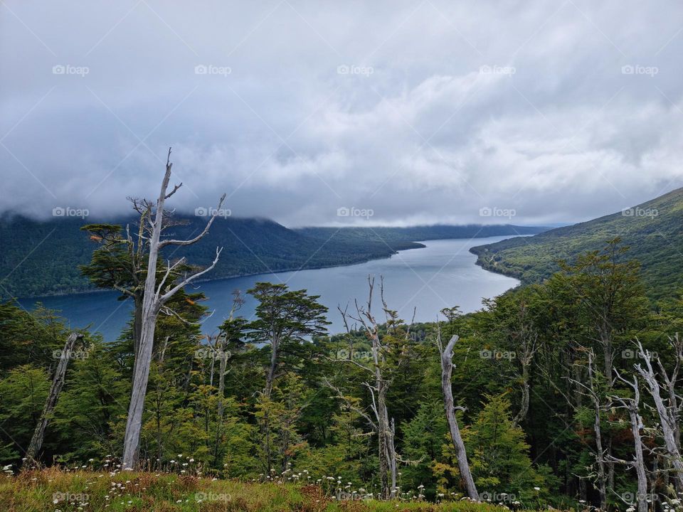 landscape of a sky with haze covering the mountains that surround the Escondido lake, green trees.