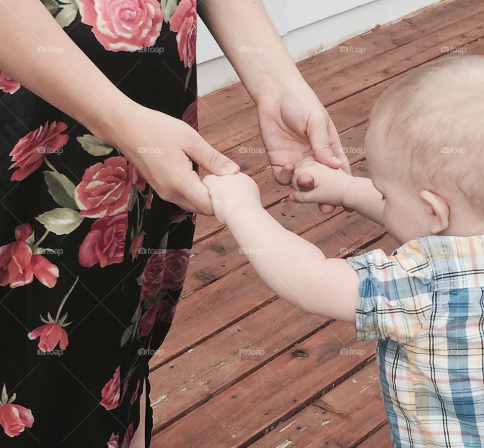 A moment caught where pregnant mommy reaches to hold baby boys hands as he slides 