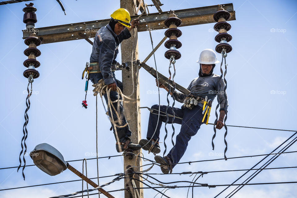 Electrician working together on the electricity pole to replace the electrical insulator