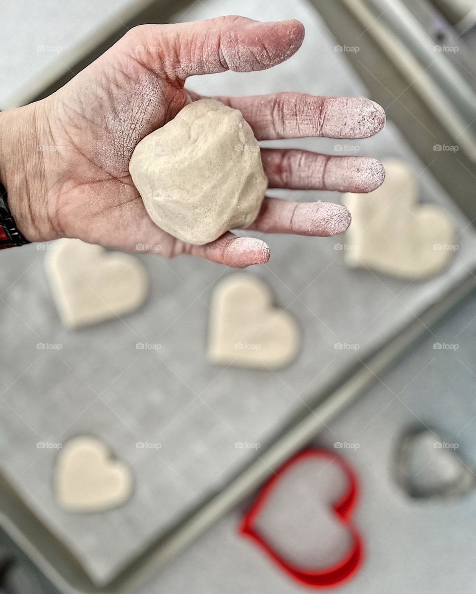 Making heart cookies, woman making sugar cookies, cookies for anniversary, heart cookies for sweetest day, baking with love, woman’s hand holding dough, woman bakes with toddler 