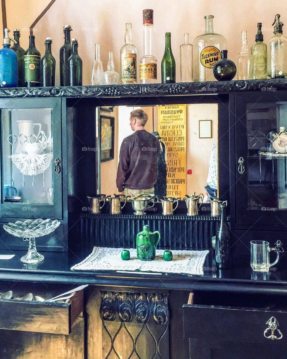 Reflection of man in the mirror surrounded by antique furniture. 