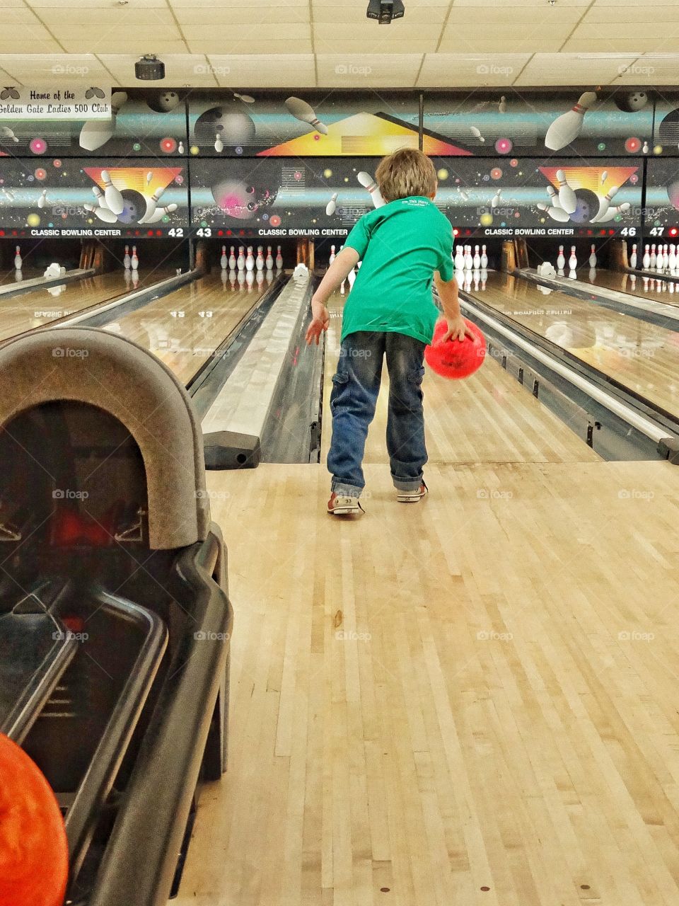 Young Boy Going Bowling. Boy Throwing A Bowling Ball On A Family Game Night
