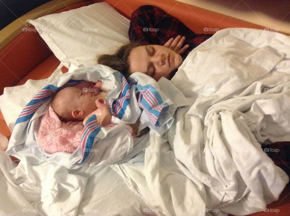 Big sister sleeping next to baby sister in hospital after open heart surgery
