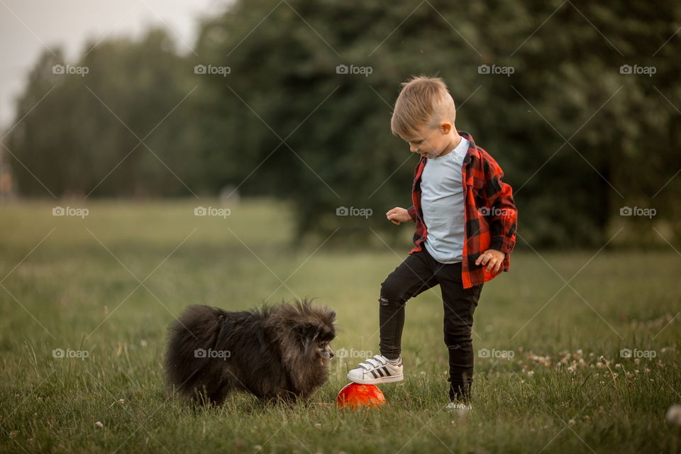 Little boy playing with his dog in soccer in a park 