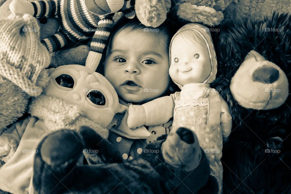 Baby hiding in stuffed animals, black and white image of baby with stuffed animals, funny baby pictures, baby with toys 