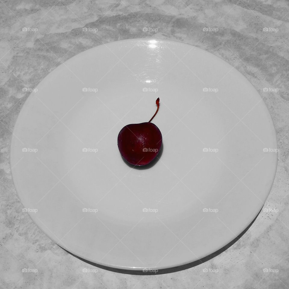 single red cherry on white plate