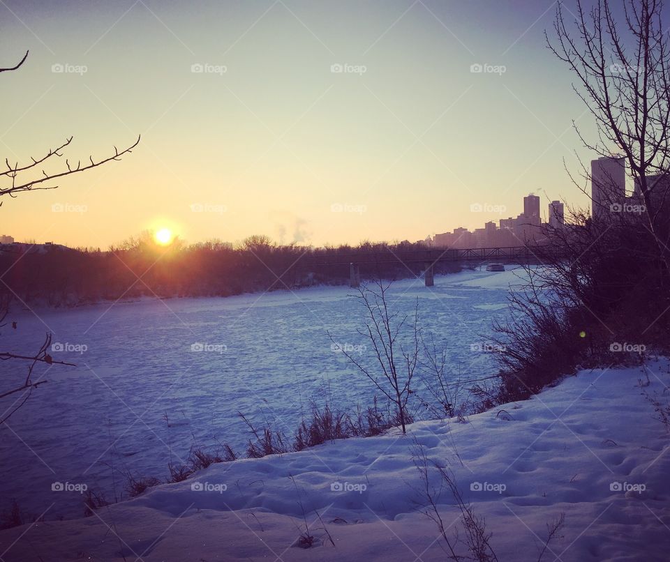 Sunset on a cold winter's day over the frozen and snow-covered North Saskatchewan River in Edmonton, Alberta, Canada
