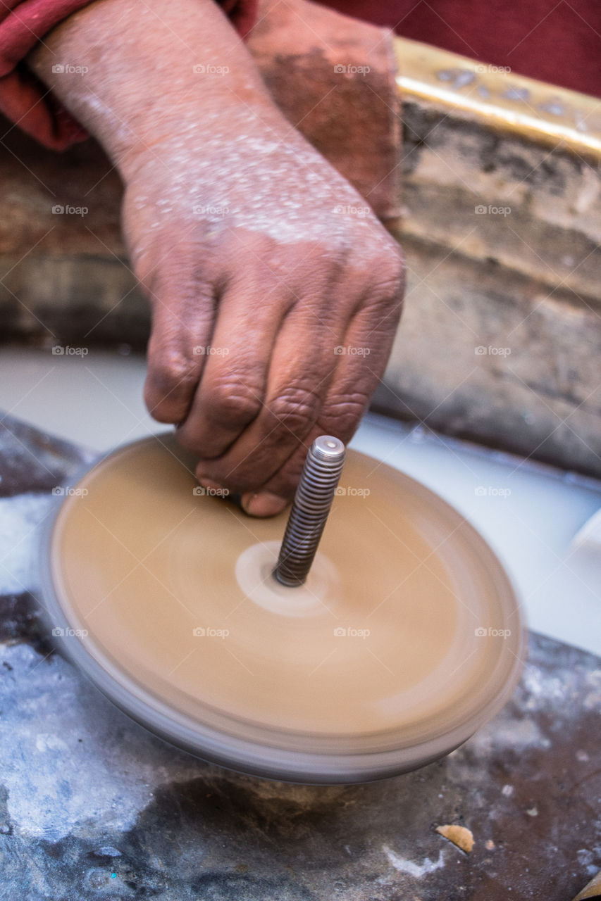 This man's job is to use this machine to turn big stones into lovely little soft and clear pieces of gems, to be used later as accessories or part of decoration. You will see different angles of the same hand and job.