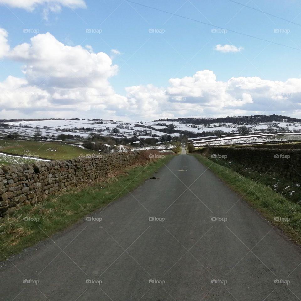 Snowy Hills in the background, road in for ground, dry stone walls