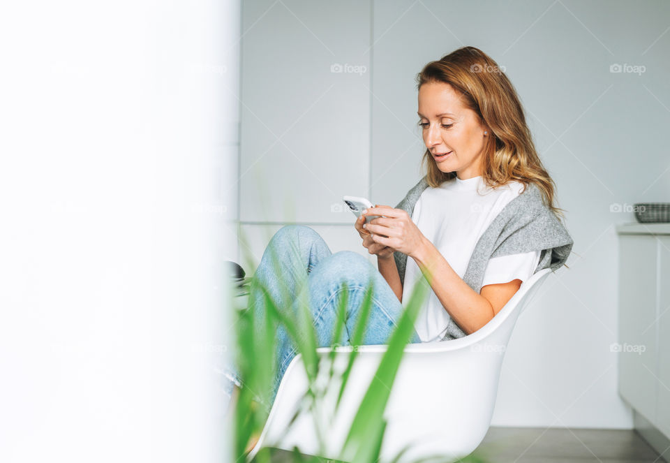 Young woman girl using mobile phone in kitchen at home 