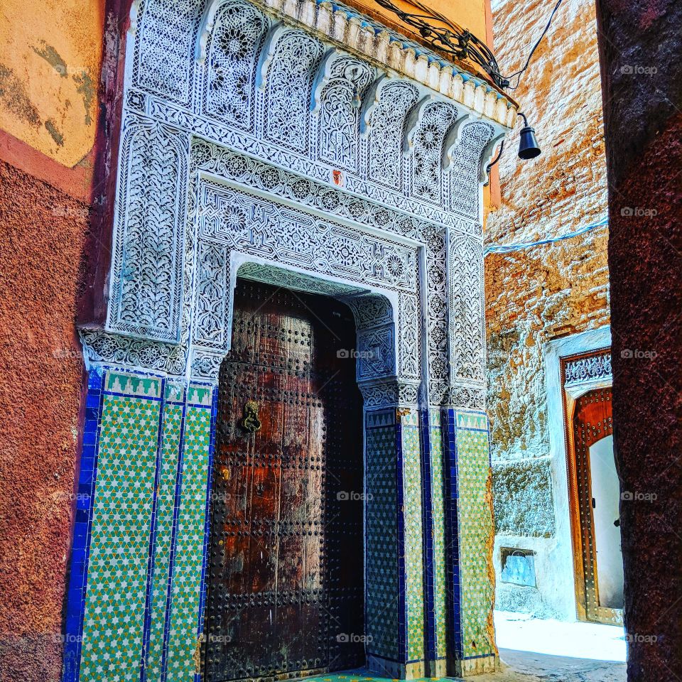 Ancient Moroccan decorated door in a narrow street of the Medina of Marrakech