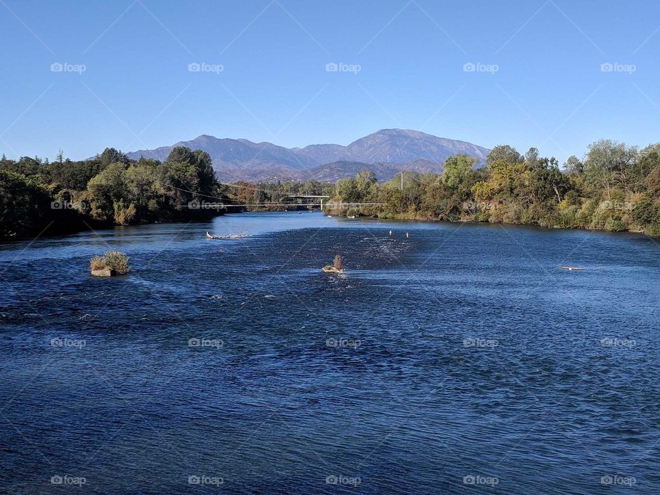 Peaceful Sacramento River in Redding, California - View from the Sundial Bridge in Turtle Bay Exploration Park - Mountains in the Background