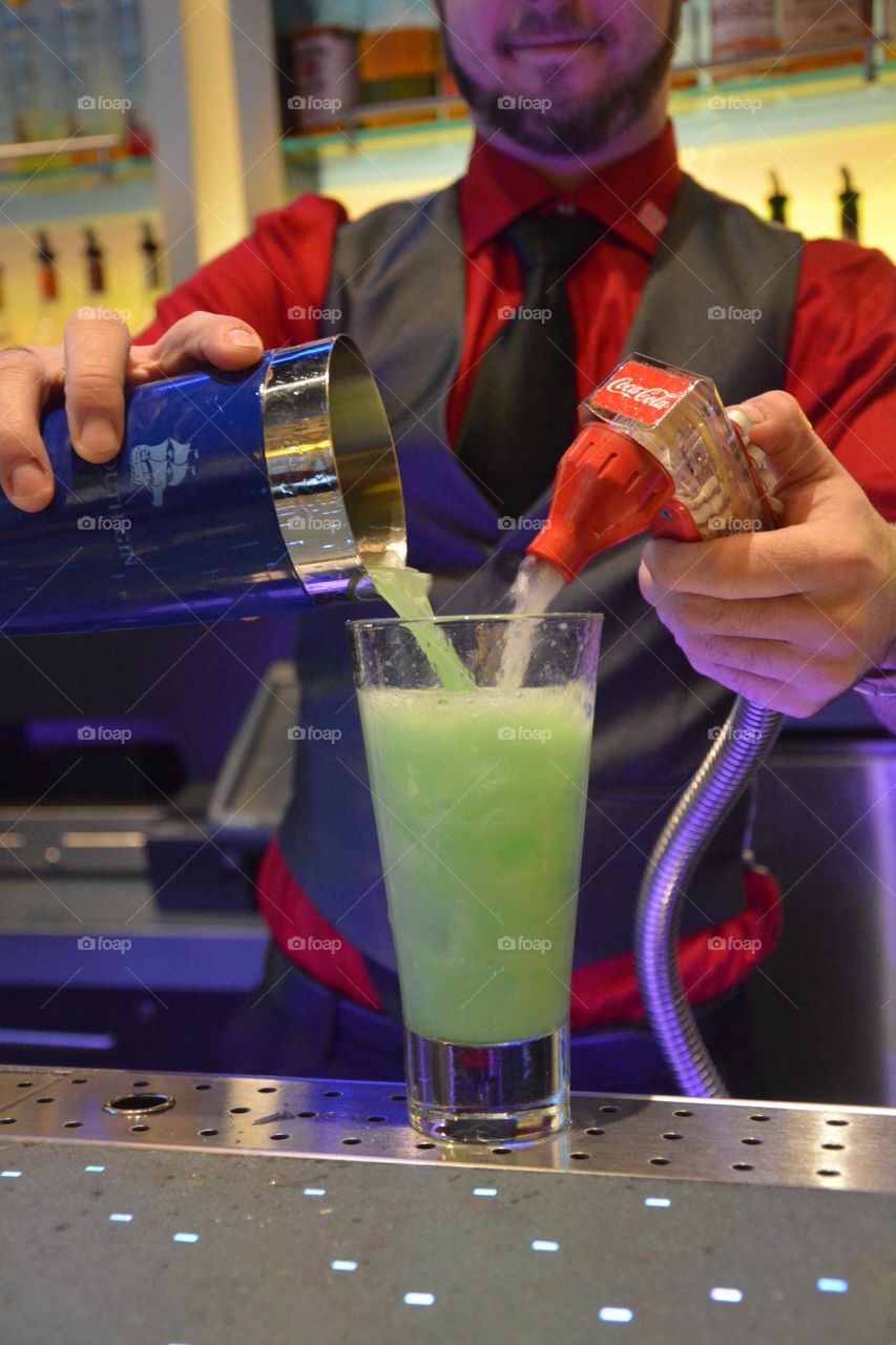 bartender pours a fancy green cocktail