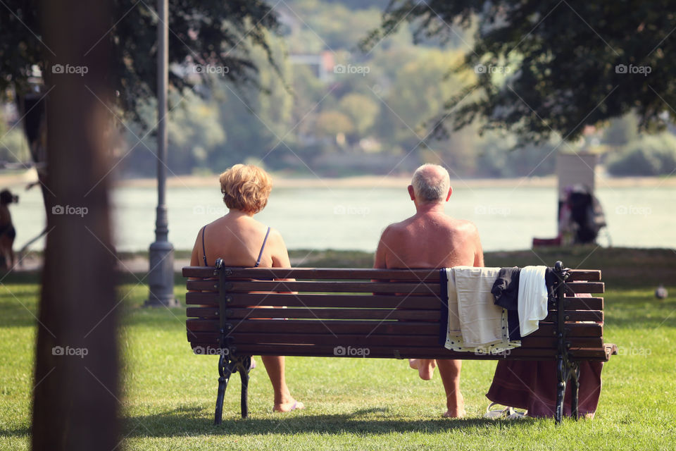 Senior couple sitting on bench enjoying sunny day