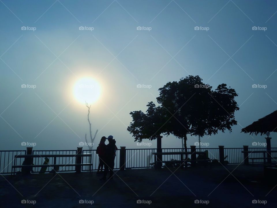 The sunrise in the morning in the mist and tourists who are admiring the beautiful nature.