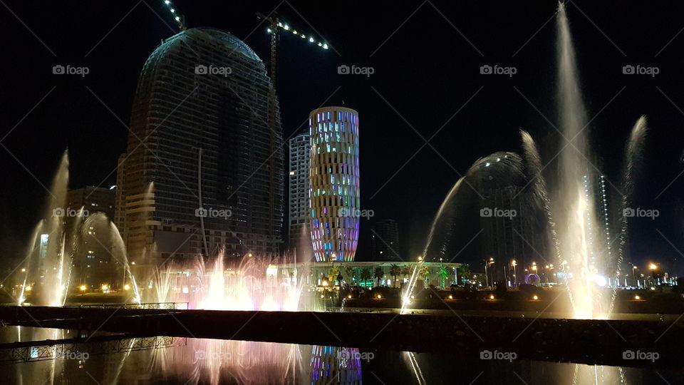 fountain with backlight against the night city skyline