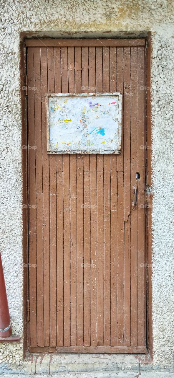 old wooden door, painted brown and noticeboard.