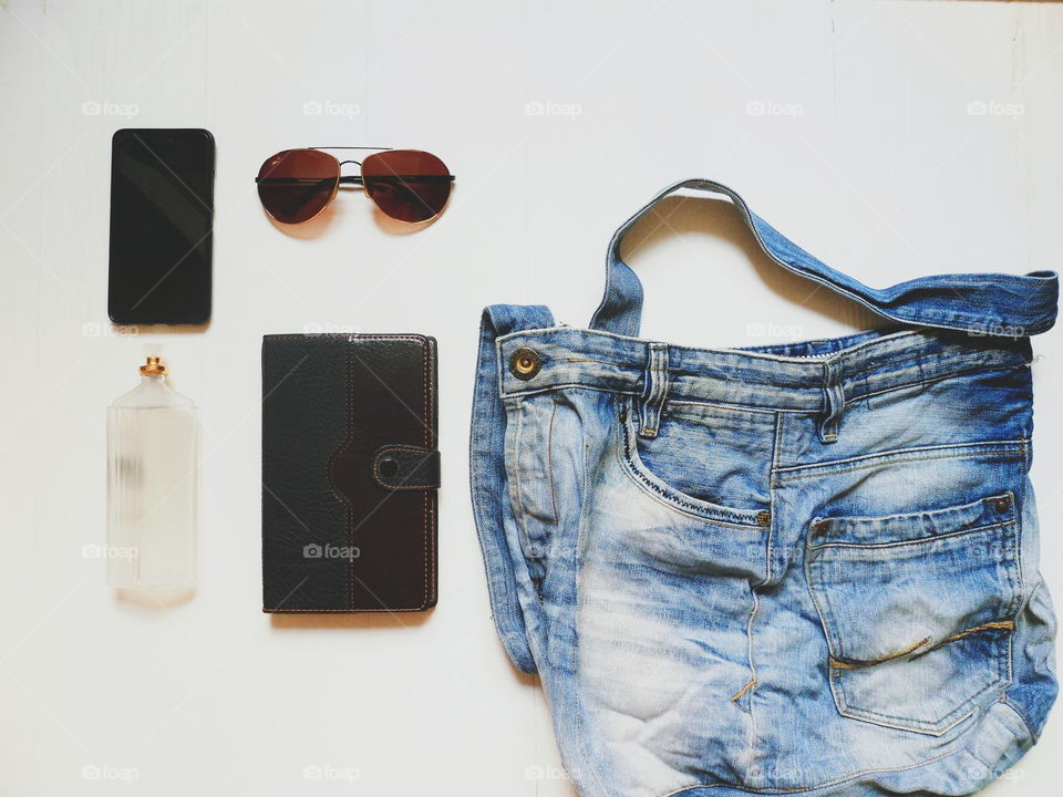 jeans bag, notebook, smartphone, sunglasses and eau de toilette on a white background