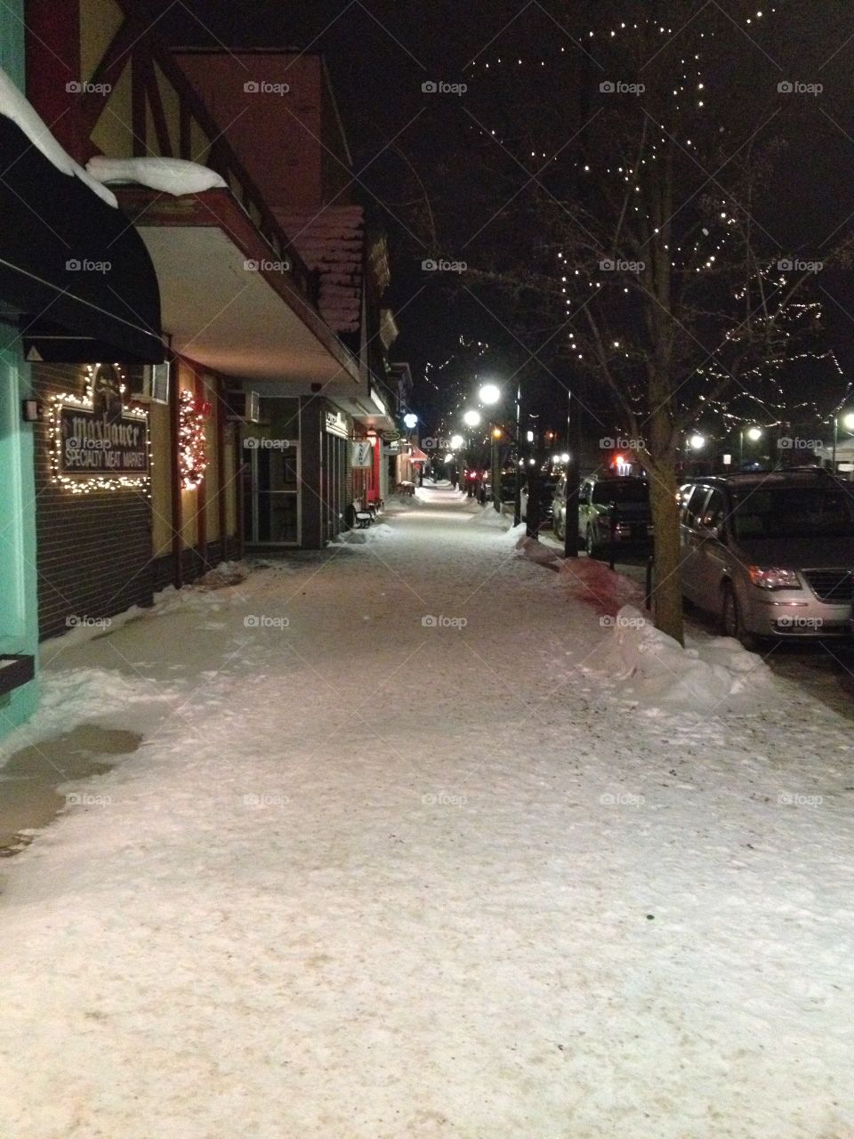 Snowy sidewalk in charming town covered in snow at night.