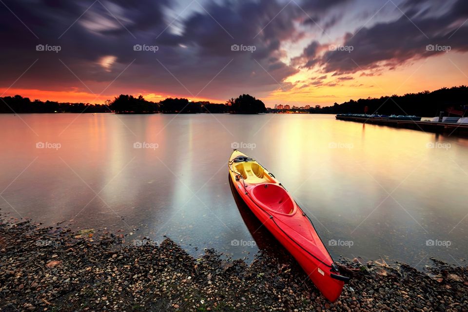 A canoe parked at the lake with beautiful sunset background