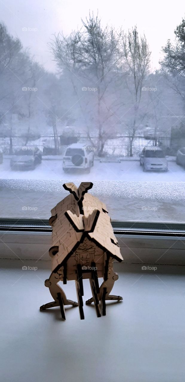 днревянный сказочный домик из русской сказки на окне с видом на зимнюю улицу