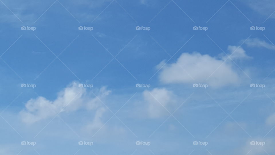 Clouds reach across a clear blue sky.