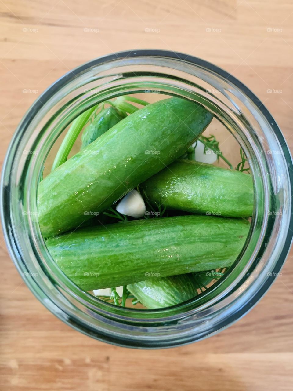 Green cucumbers in a jar just before becoming pickles