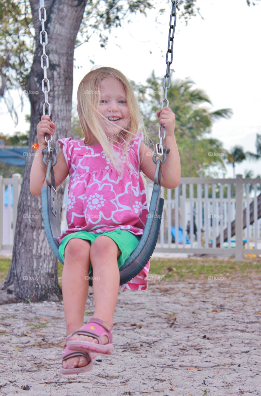 Little girl swinging on a swing set 