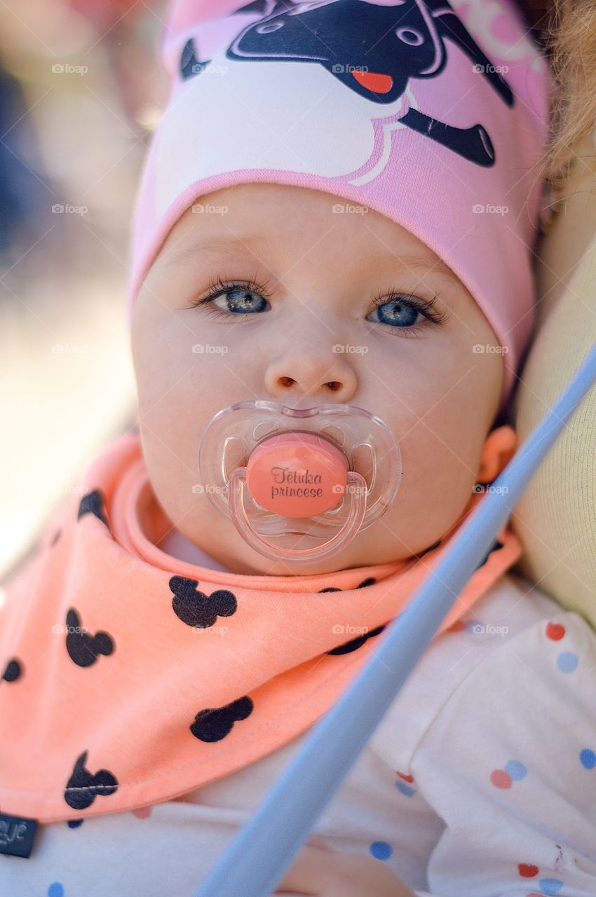 Baby girl looking sraight at camera with crystal clear blue eyes.