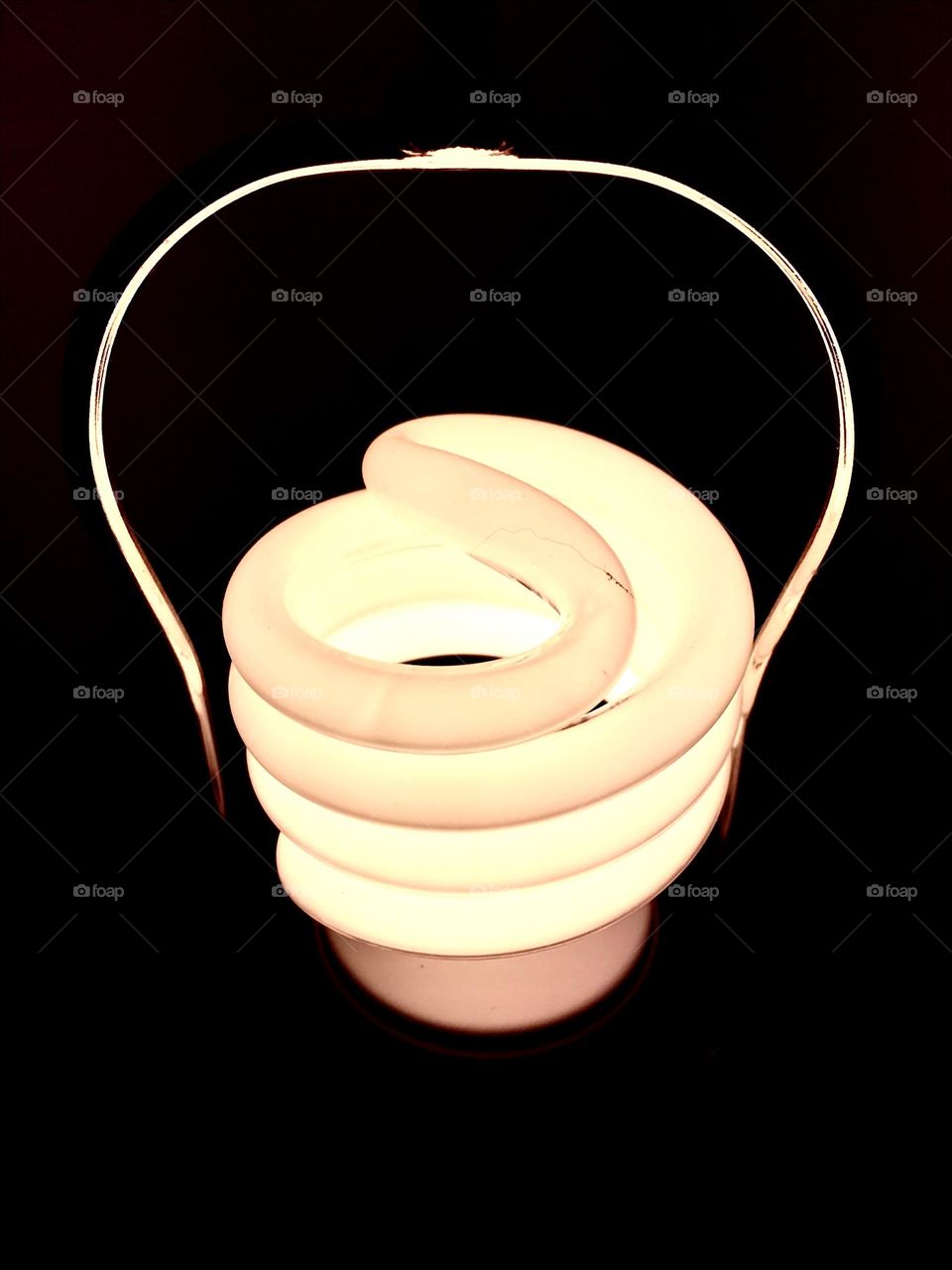 Illuminated lightbulb isolated on black background backdrop, spiral tubular Australian type, minimalist, conceptual image ie technology, idea, concept, electricity. Room for text copy space 