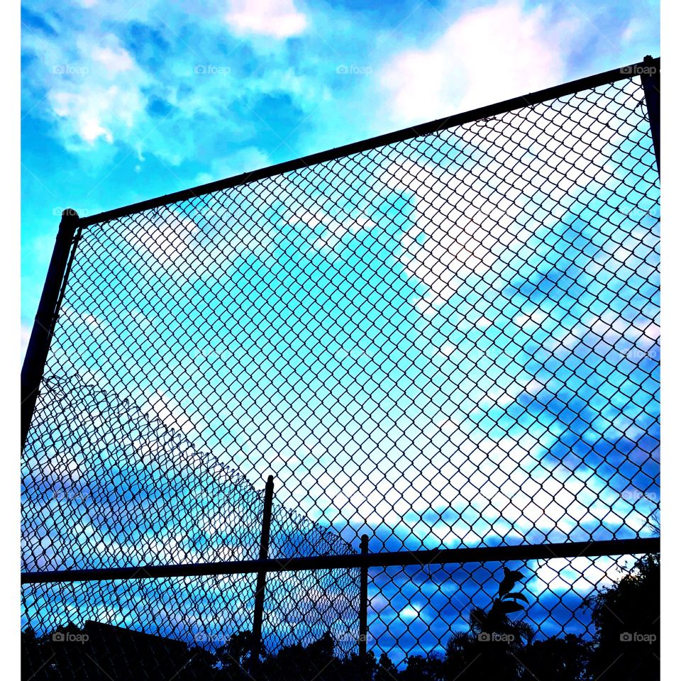 Clouds on Sunday late afternoon through a chain length fence.