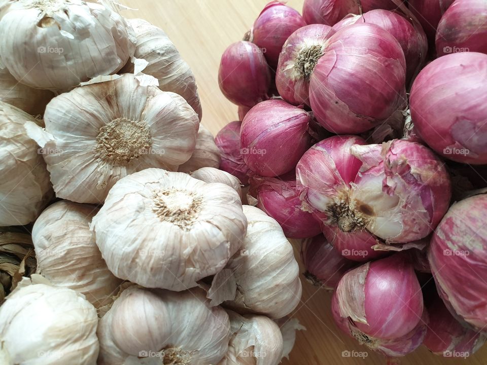 Bundles of organic Thai garlic and shallots the most widely used ingredients in Thai cuisine in a basket on a bamboo mat - Top view closeup