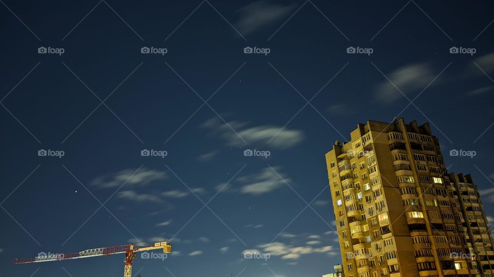 night sky with stars and clouds on the background of a residential building