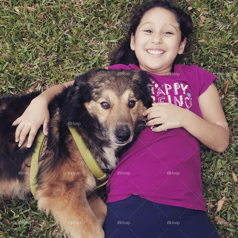 Smiling girl lying on grass with pet dog