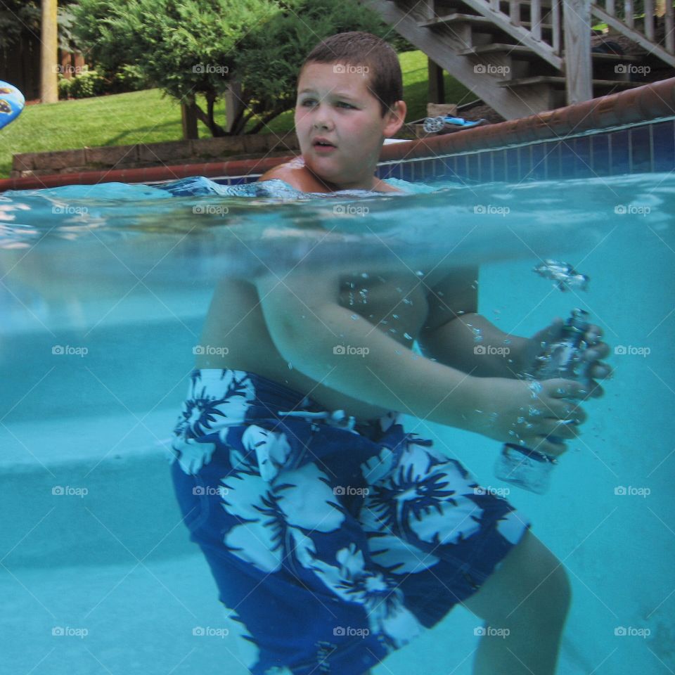 Boy holding bottle in swimming pool