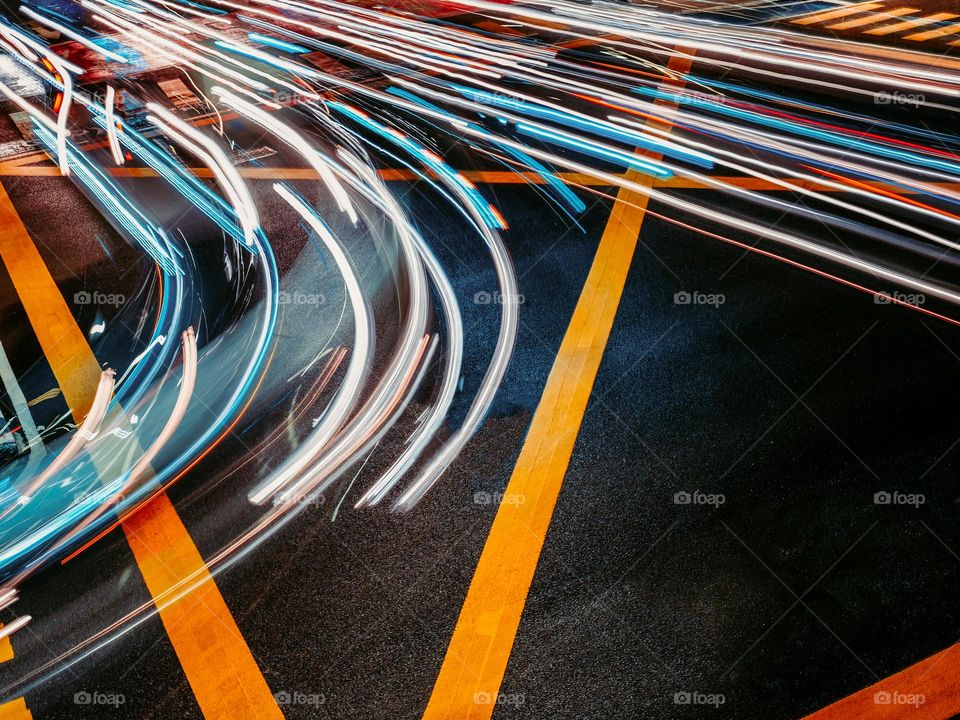 Long exposure of automotive movements driving through a street juction at night