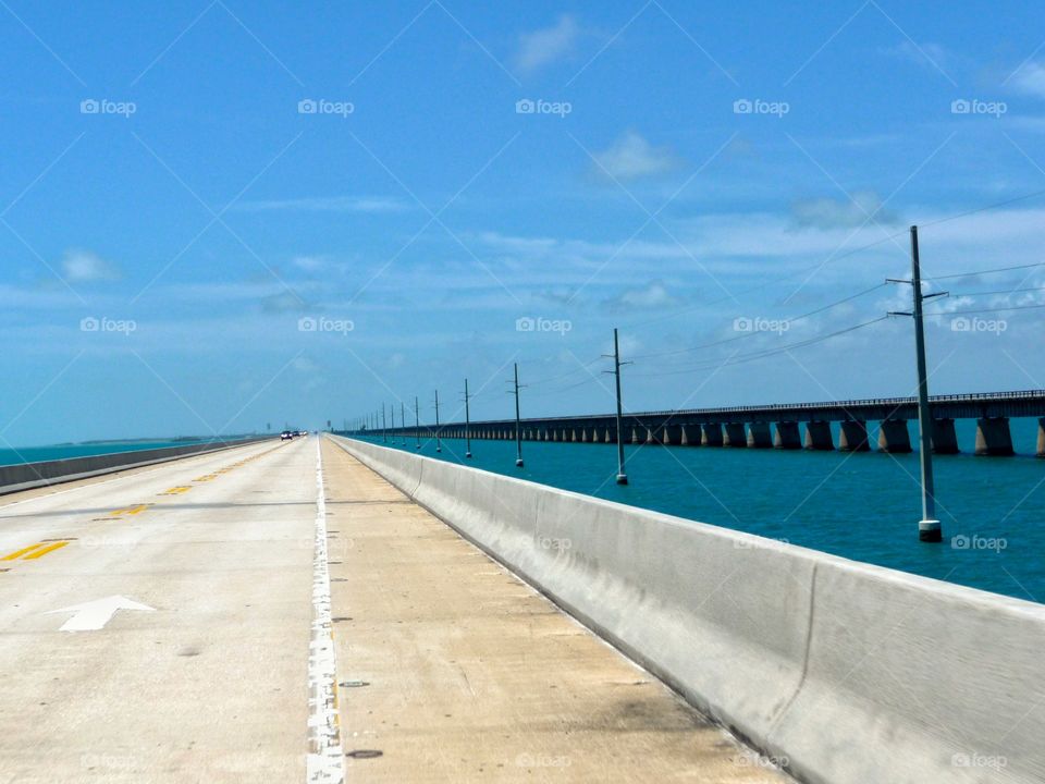 Bridge over the ocean. Blue sky, blue sea and a long, long bridge leading to a beautiful place.