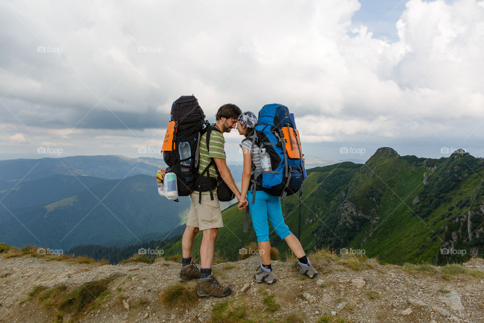 loving couple in the mountains with backpacks look into each other's eyes