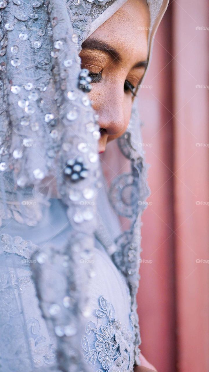 Portrait of young and beautiful Asian muslim woman wearing silver robe with matching hijab and headscarf, for the wedding.