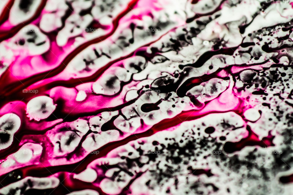 Black and pink refill ink spilled onto the white sink and the ink mixed into abstract blobs and patterns.