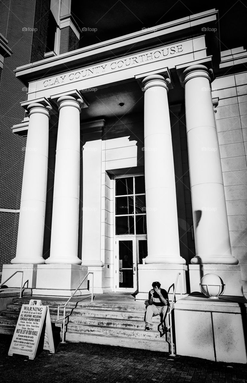 A man sitting in front of a courthouse.
