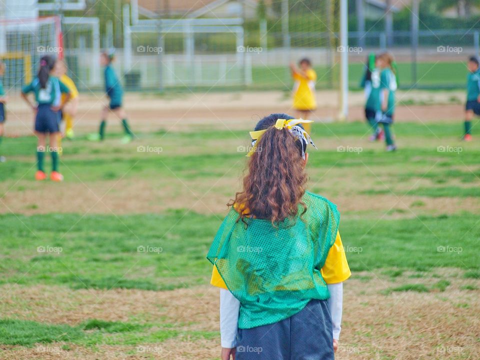 A rear view of girl standing on football pitch