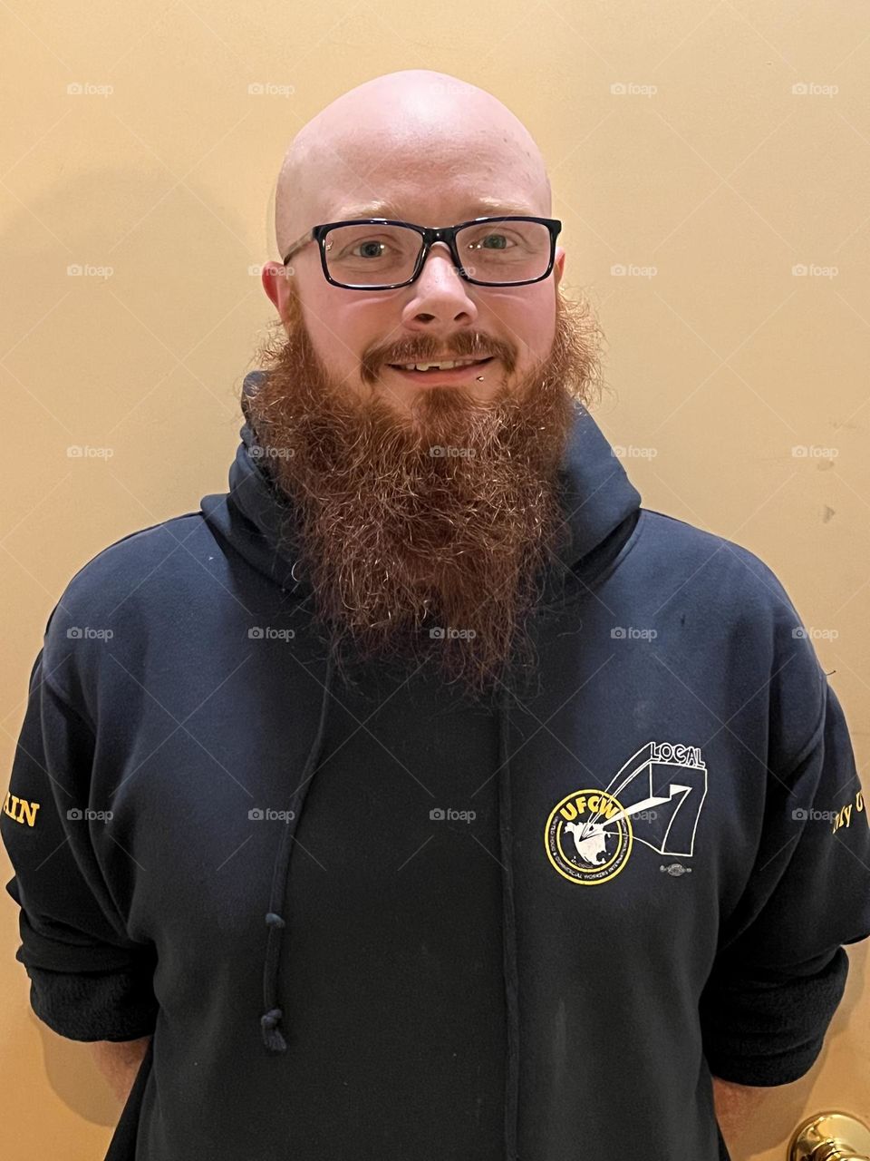 Bald man with red beard and dark blue hoodie.