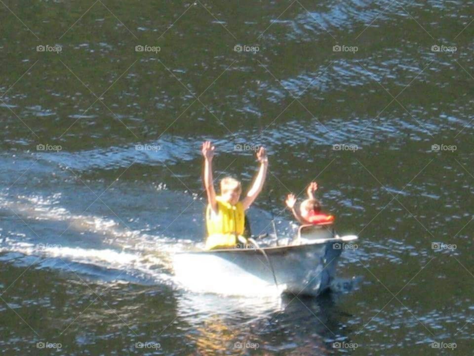 Kid's in a boat doing the wave.