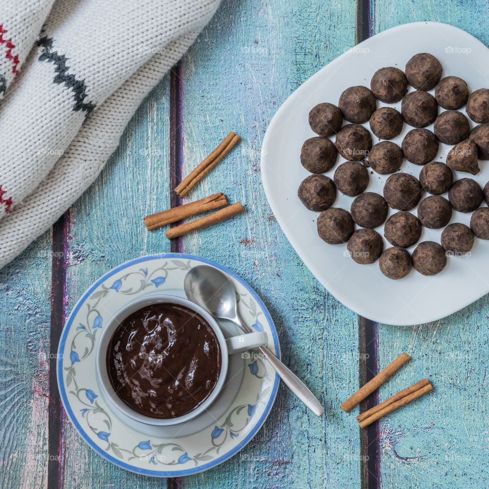 Cup of hot chocolate and strawberry truffles on a wooden tablr