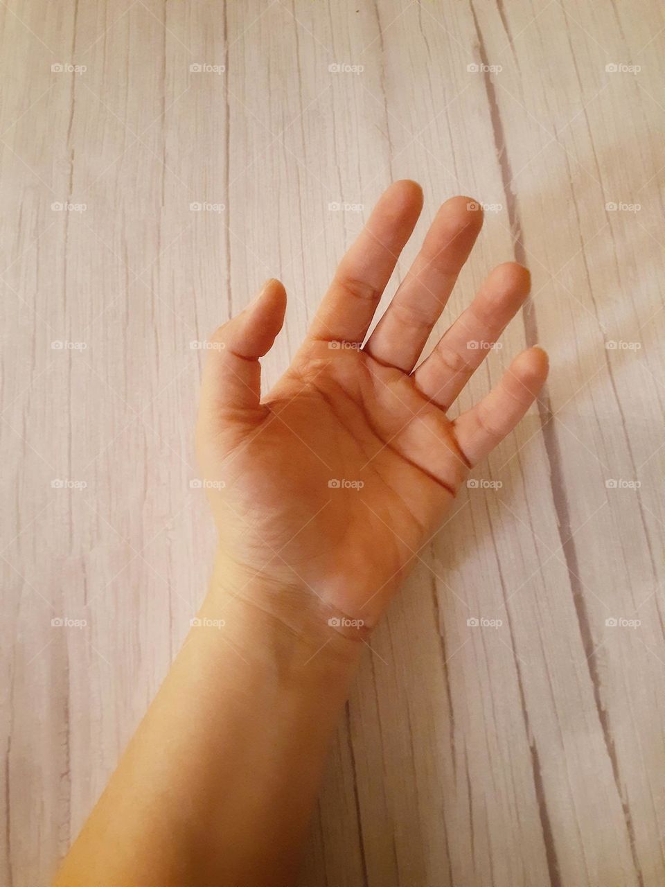 A close up of a caucasian woman hand and wrist. Her hand is palm up and her fingers spread apart.