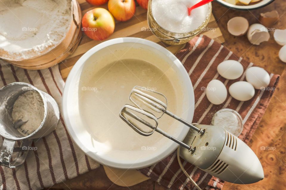 Making an apple pie dough using eggs, flour, sugar and apples.