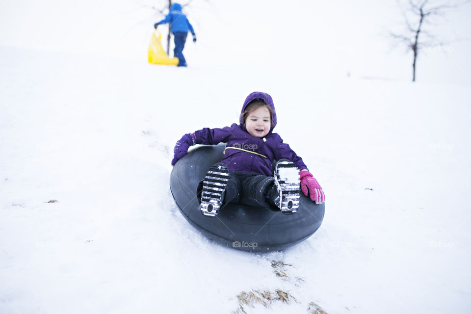 Girl sledding down a hill in the winter 