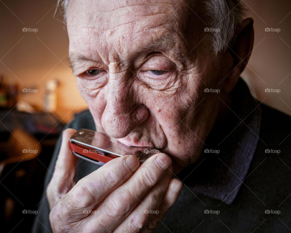 Portrait of old man playing harmonica
