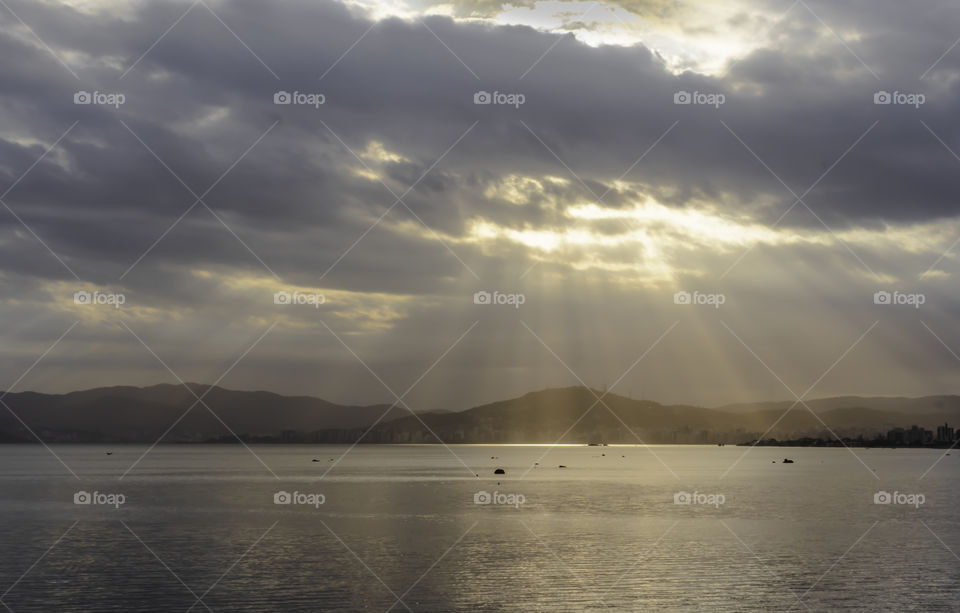 sunlight leaking through the clouds and hitting the sea